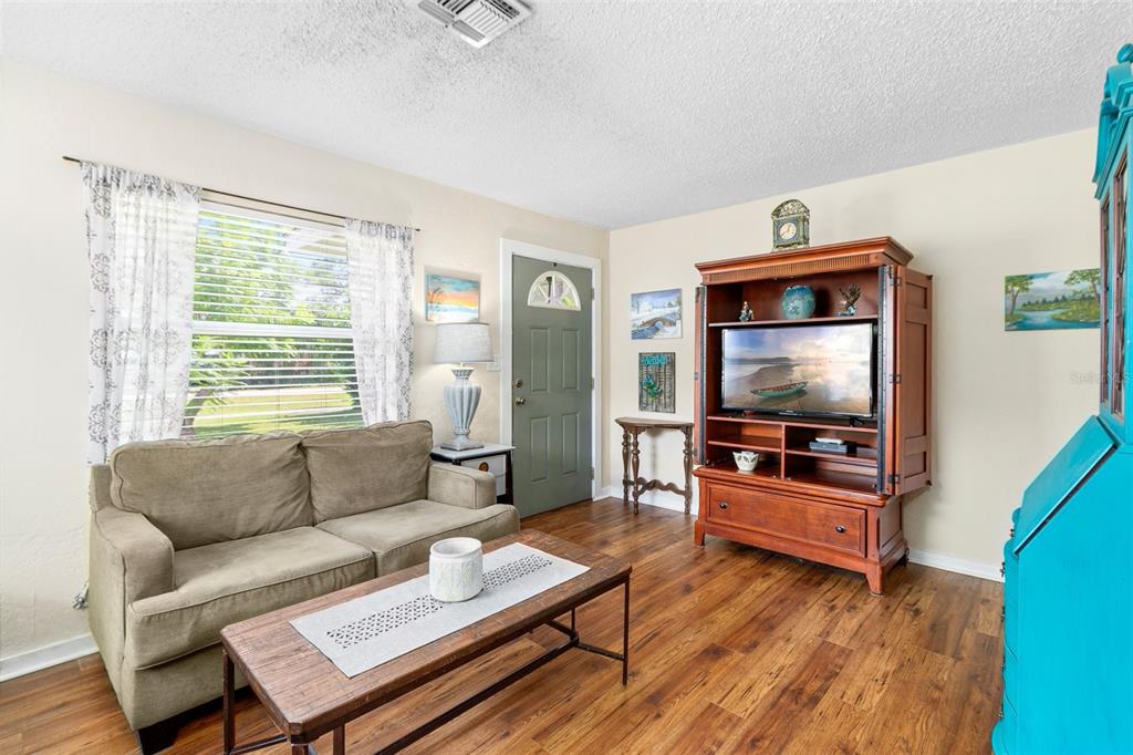 A living room features a tan sofa, wooden coffee table, and a large media cabinet — 6030 62ND STREET N, ST PETERSBURG, FL
