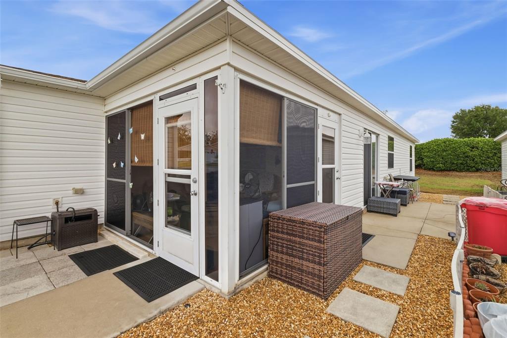 A gravel walkway with concrete pavers sits between two white residential buildings — 1639 S ALLENDALE PLACE, THE VILLAGES, FL