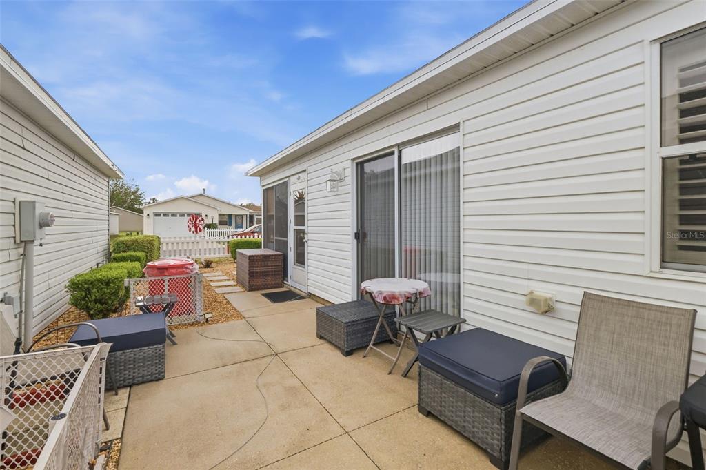 A view of a house exterior featuring a garage, a screened-in porch, and concrete walkways — 1639 S ALLENDALE PLACE, THE VILLAGES, FL