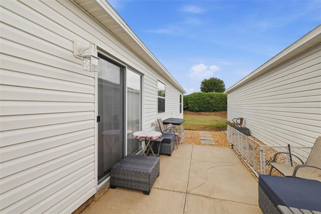 A sliding glass door with a bamboo shade opens to a patio and fenced yard — 1639 S ALLENDALE PLACE, THE VILLAGES, FL