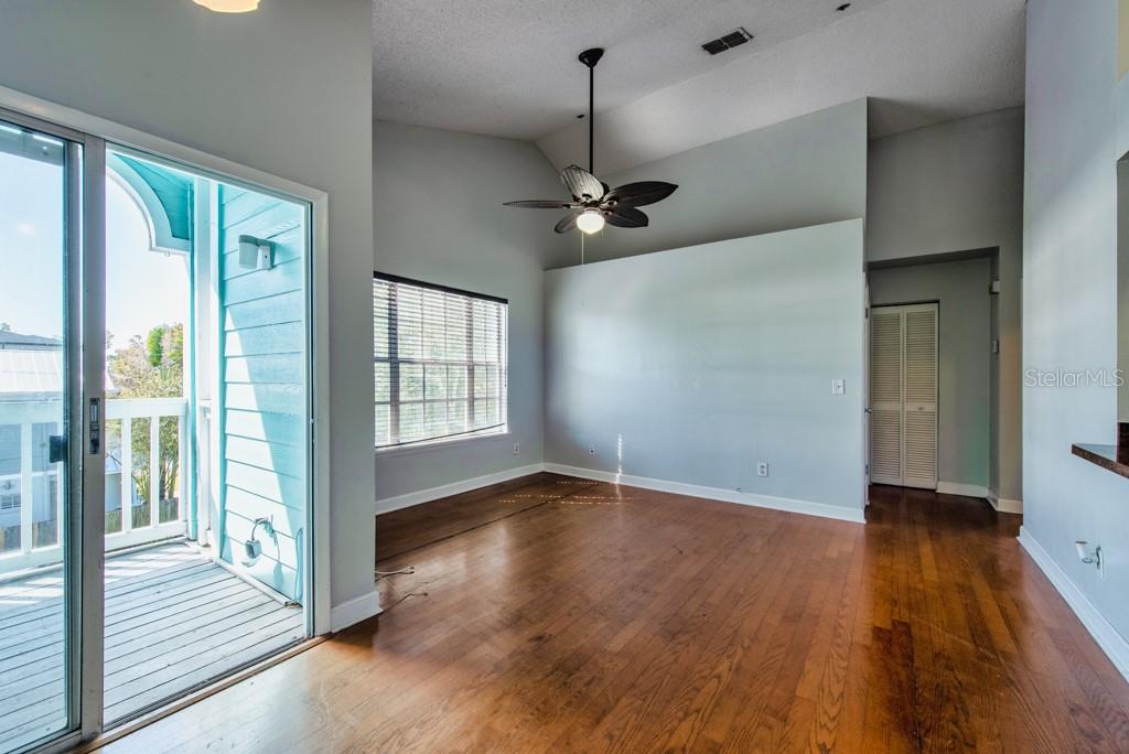 A living room with light wood flooring, a vaulted ceiling, a ceiling fan, and a balcony — 3002 W CLEVELAND STREET UNIT D11, TAMPA, FL