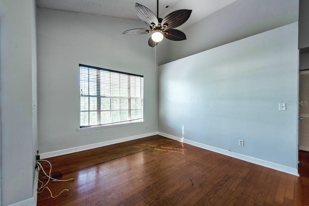 An empty room with light gray walls, wood-look flooring, a ceiling fan, and a window — 3002 W CLEVELAND STREET UNIT D11, TAMPA, FL