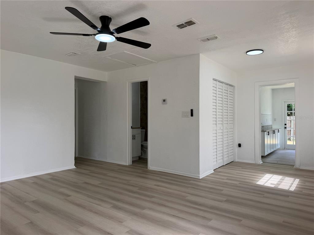 A bright room with light wood-look flooring, a ceiling fan, and white walls — 1102 E 108TH AVENUE, TAMPA, FL