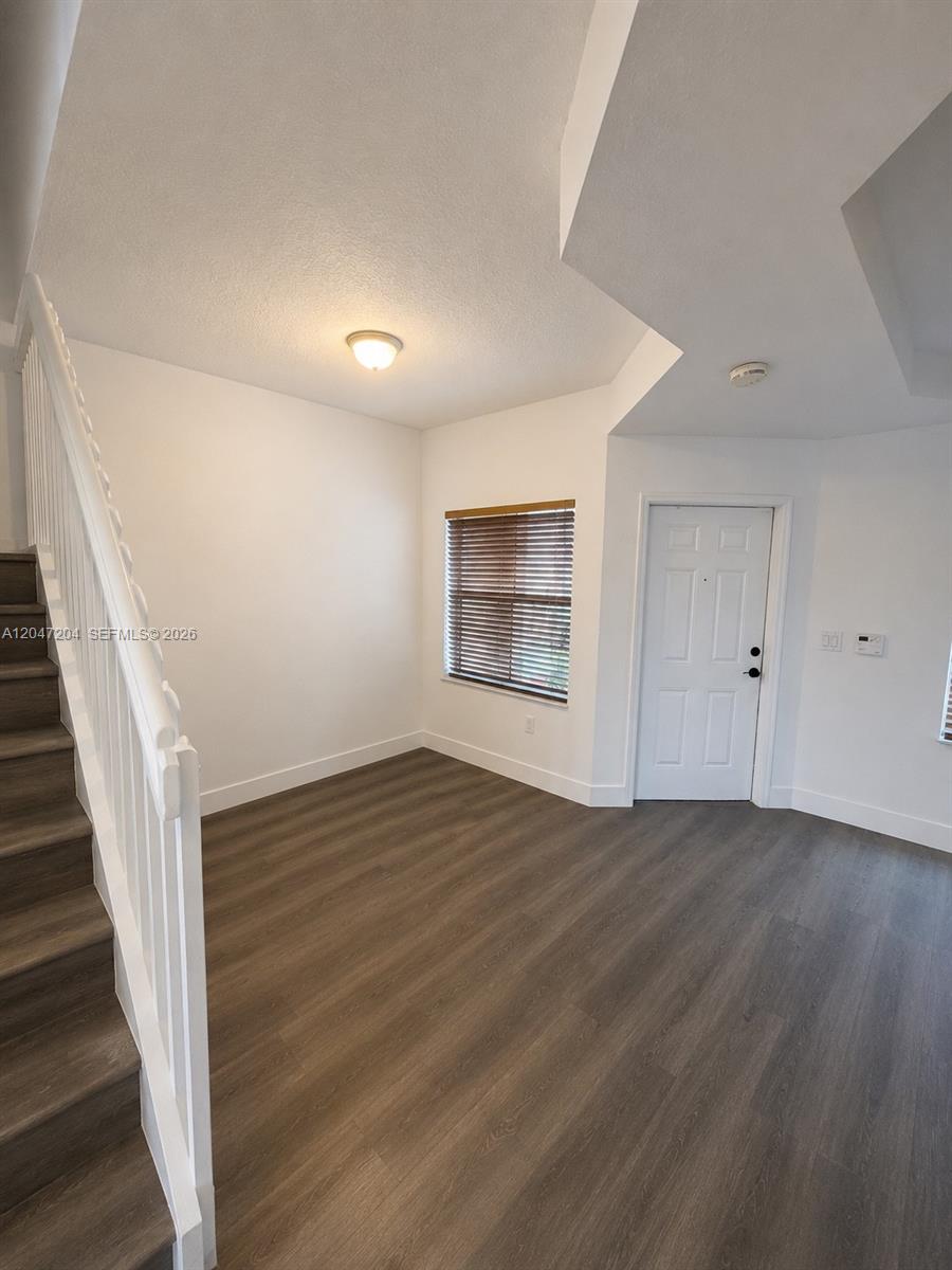 This room features wood-look flooring, a staircase with a white railing, and a white door — 6016 NW 116th Pl # 406, Doral FL 33178, DORAL, FL