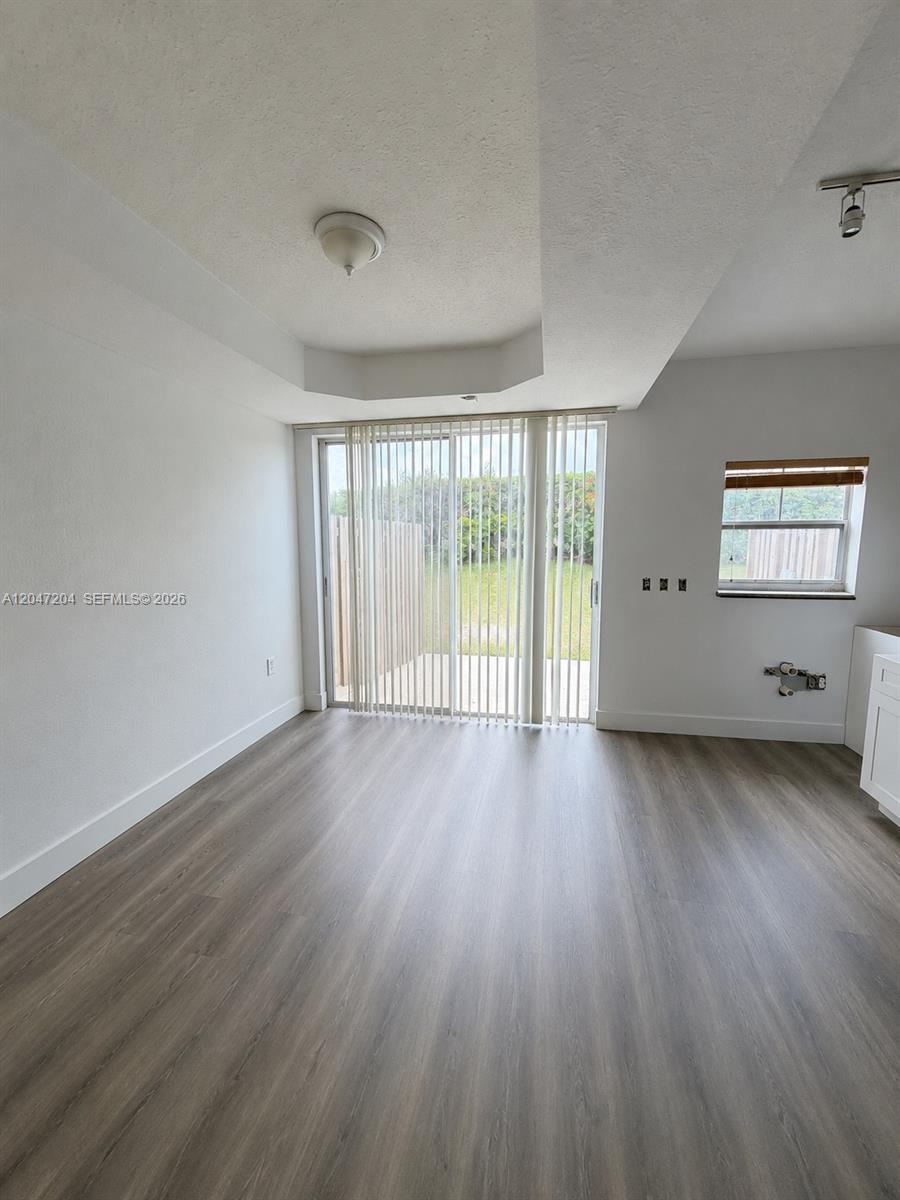 An empty room features wood-look flooring, a sliding glass door, and a small window — 6016 NW 116th Pl # 406, Doral FL 33178, DORAL, FL