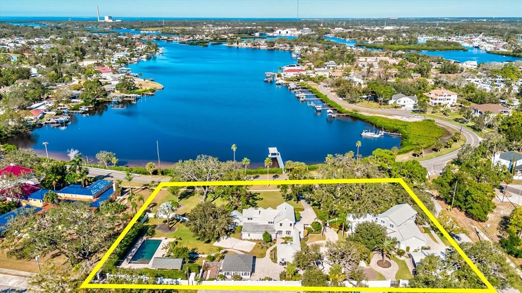 An aerial view shows a large waterfront property with a pool, multiple buildings, and trees — 518 RIVERSIDE DRIVE, TARPON SPRINGS, FL