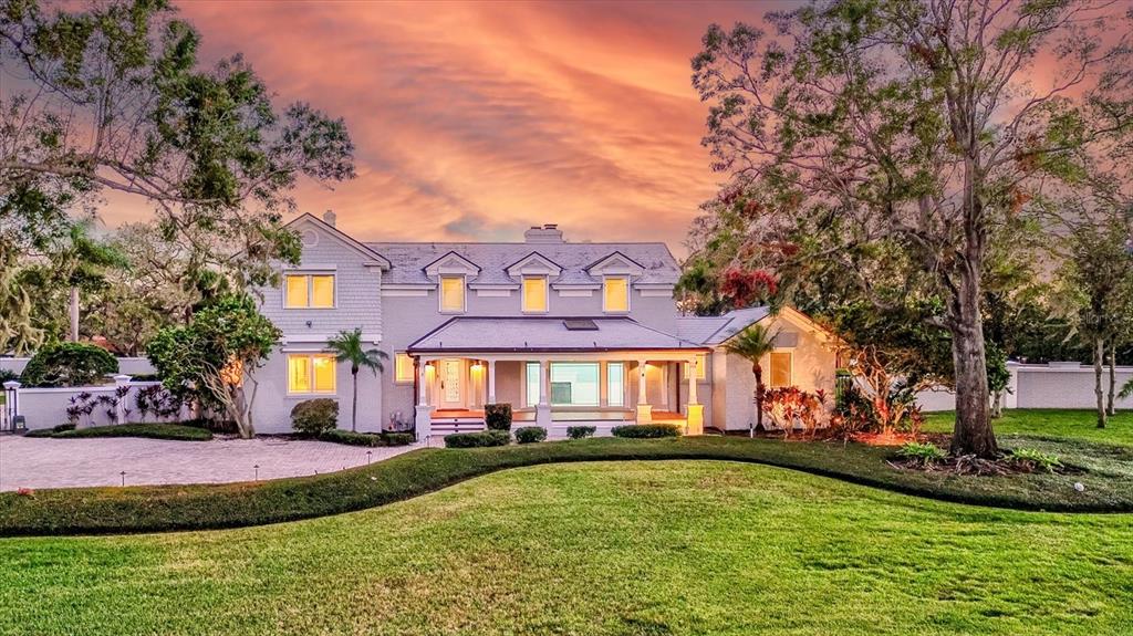 A two-story house with a covered front porch and a large lawn at sunset — 518 RIVERSIDE DRIVE, TARPON SPRINGS, FL