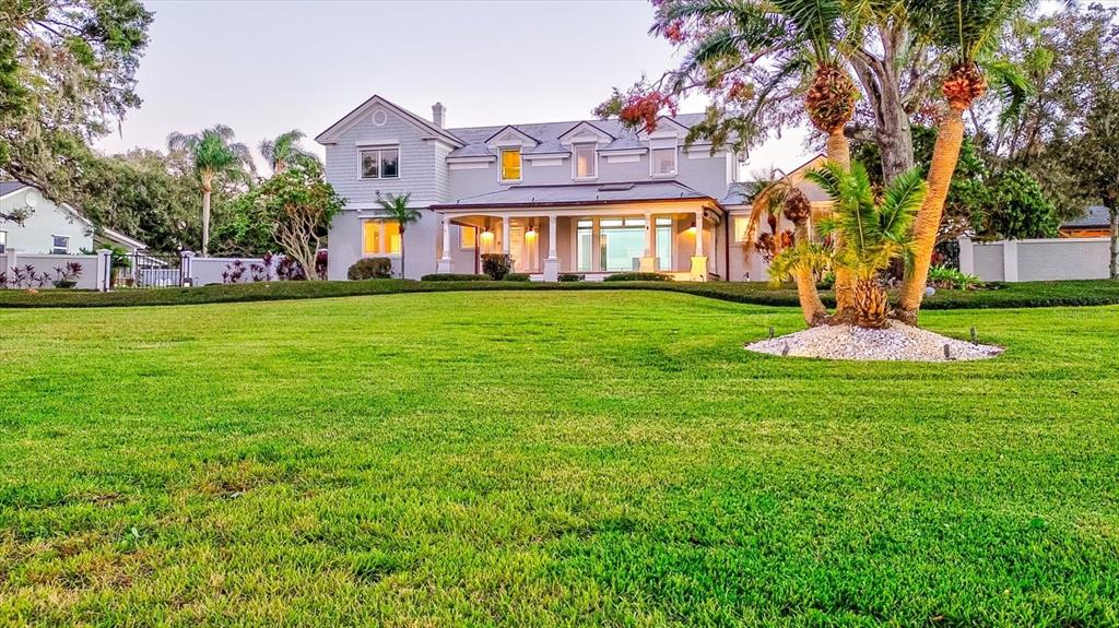 A two-story house with a large lawn and palm trees under a clear sky — 518 RIVERSIDE DRIVE, TARPON SPRINGS, FL