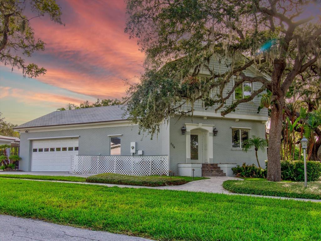 A two-story gray house with a garage and a large oak tree in the front yard — 518 RIVERSIDE DRIVE, TARPON SPRINGS, FL