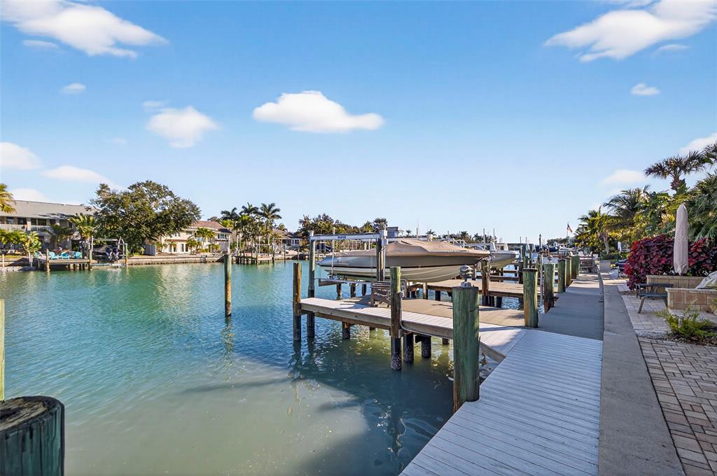 A boat lift and wooden dock extend into a canal lined with houses and palm trees — 903 PINELLAS BAYWAY S UNIT 308, TIERRA VERDE, FL