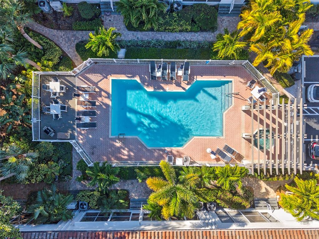 An aerial view shows a swimming pool with a deck, lounge chairs, and a pergola — 903 PINELLAS BAYWAY S UNIT 308, TIERRA VERDE, FL