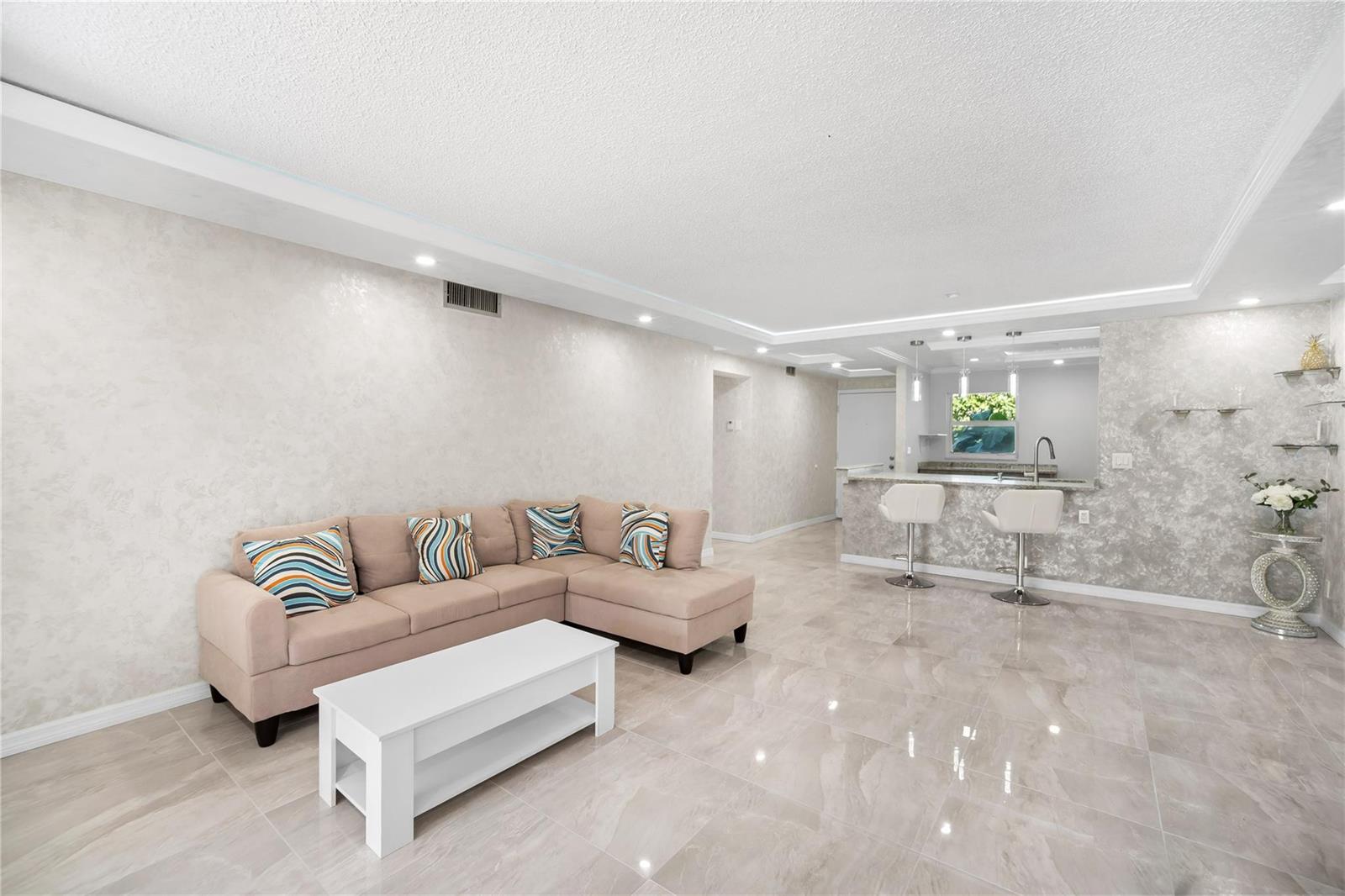 A living room with a beige sectional sofa, white coffee table, and tiled floors — 2615 NE 3rd Court # 220, Boynton Beach FL 33435, BOYNTON BEACH, FL