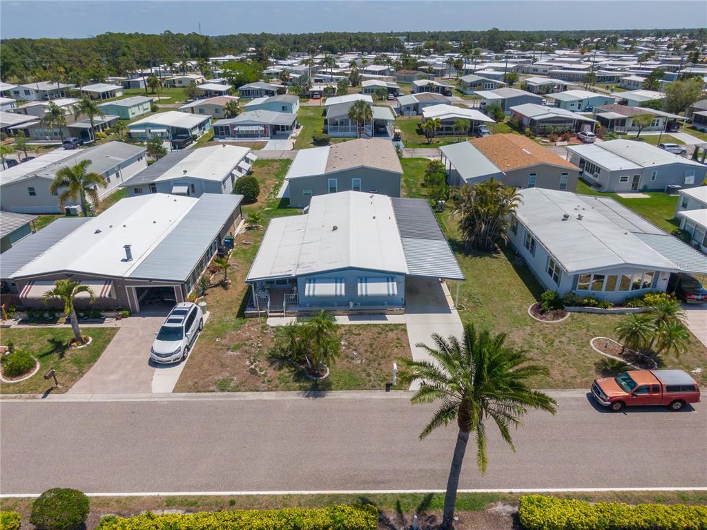 An aerial view shows a light blue manufactured home with a metal roof and carport — 172 PALM HARBOR DRIVE, NORTH PORT, FL
