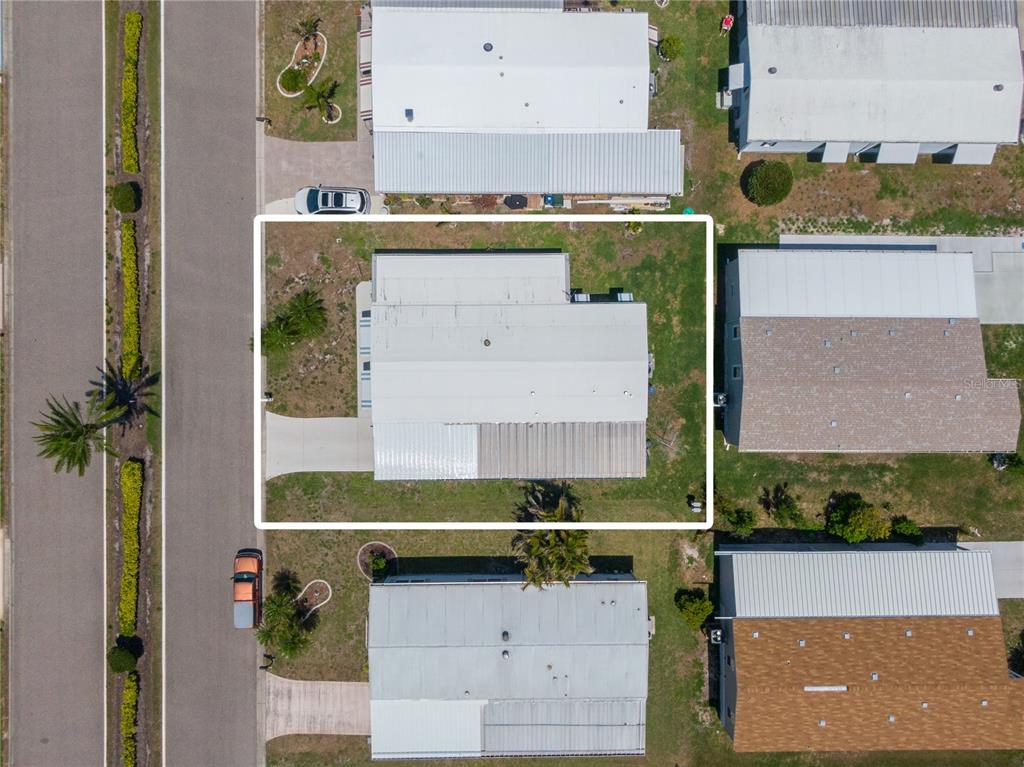 An aerial view shows a single-story mobile home with a metal roof and concrete driveway — 172 PALM HARBOR DRIVE, NORTH PORT, FL