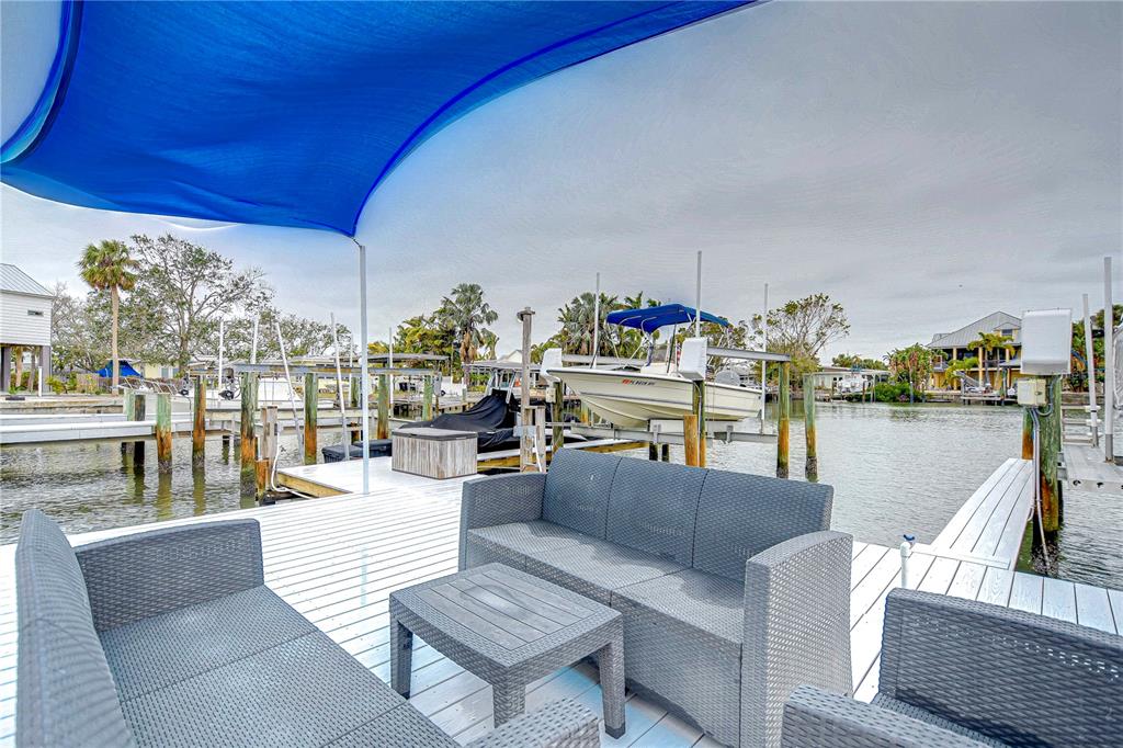 A blue apartment building sits beside a wooden dock with outdoor furniture and a shade sail — 300 VENETIAN DRIVE UNIT 2, CLEARWATER, FL