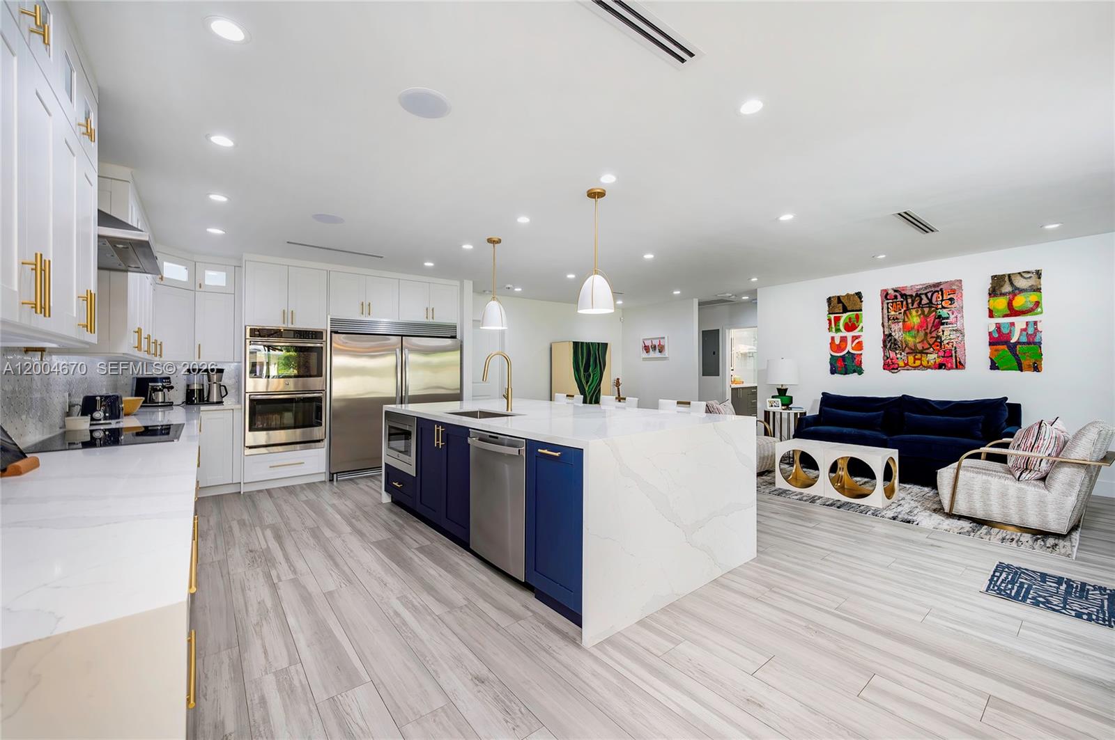 A modern kitchen features a blue island with a white countertop and stainless steel appliances — 831 Cortez St, Coral Gables FL 33134, CORAL GABLES, FL