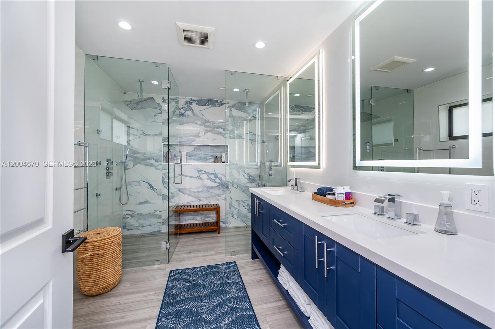 A modern bathroom features a blue double vanity, white countertops, and a glass-enclosed shower — 831 Cortez St, Coral Gables FL 33134, CORAL GABLES, FL