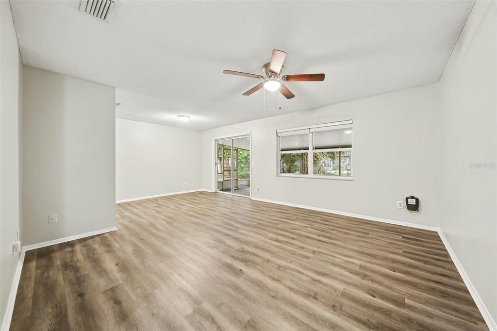 A spacious living room features light gray walls, wood-look flooring, a ceiling fan, and sliding doors — 702 GREGORY COURT, ALTAMONTE SPRINGS, FL
