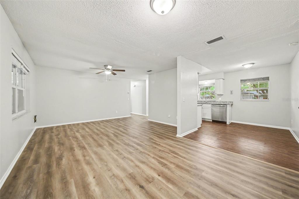 An open-concept living area with light wood-look flooring connects to a kitchen with stainless appliances — 702 GREGORY COURT, ALTAMONTE SPRINGS, FL