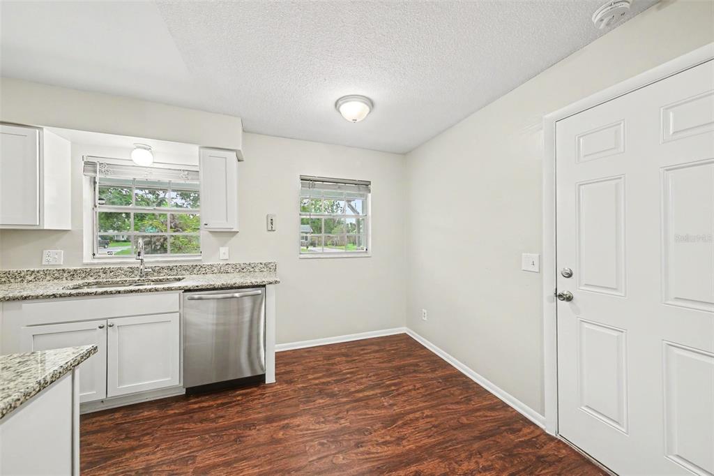 A kitchen with white cabinets, granite countertops, stainless steel appliances, and wood-look flooring — 702 GREGORY COURT, ALTAMONTE SPRINGS, FL