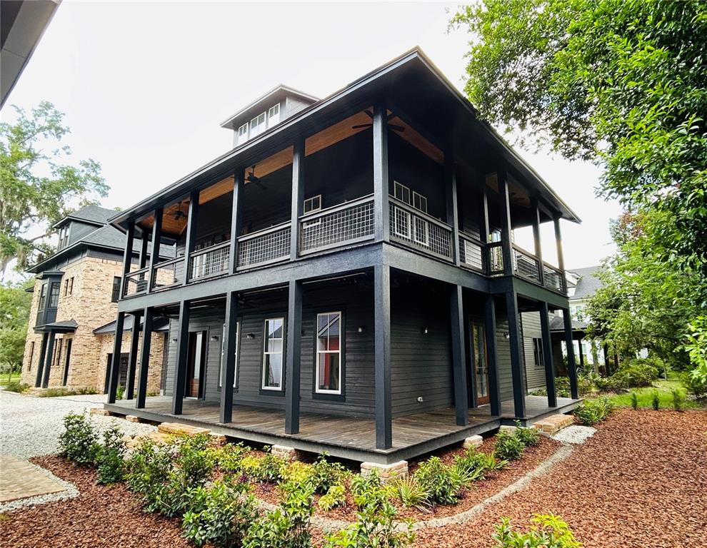 A two-story dark-painted house features wrap-around porches on both levels and a metal roof — 296 NW 12TH AVENUE, GAINESVILLE, FL