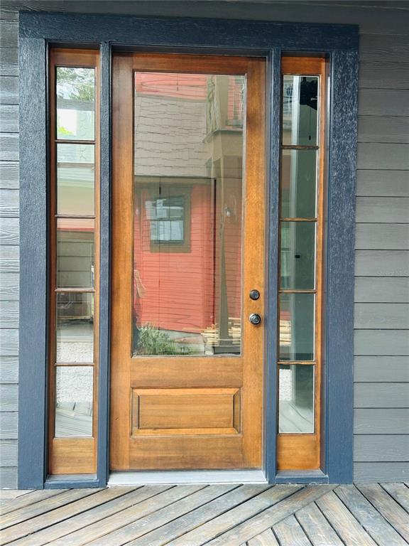 A wooden front door with glass panels and sidelights is set against dark gray siding — 296 NW 12TH AVENUE, GAINESVILLE, FL