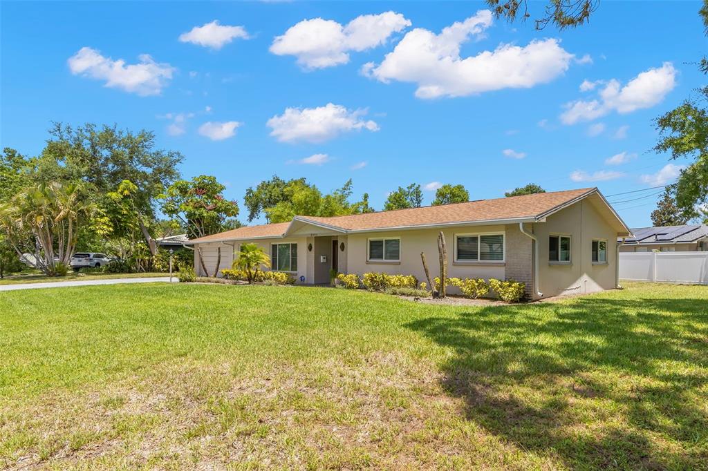 A single-story ranch-style house with a tan exterior, brown roof, and a large front lawn — 2391 66TH TERRACE S, ST PETERSBURG, FL