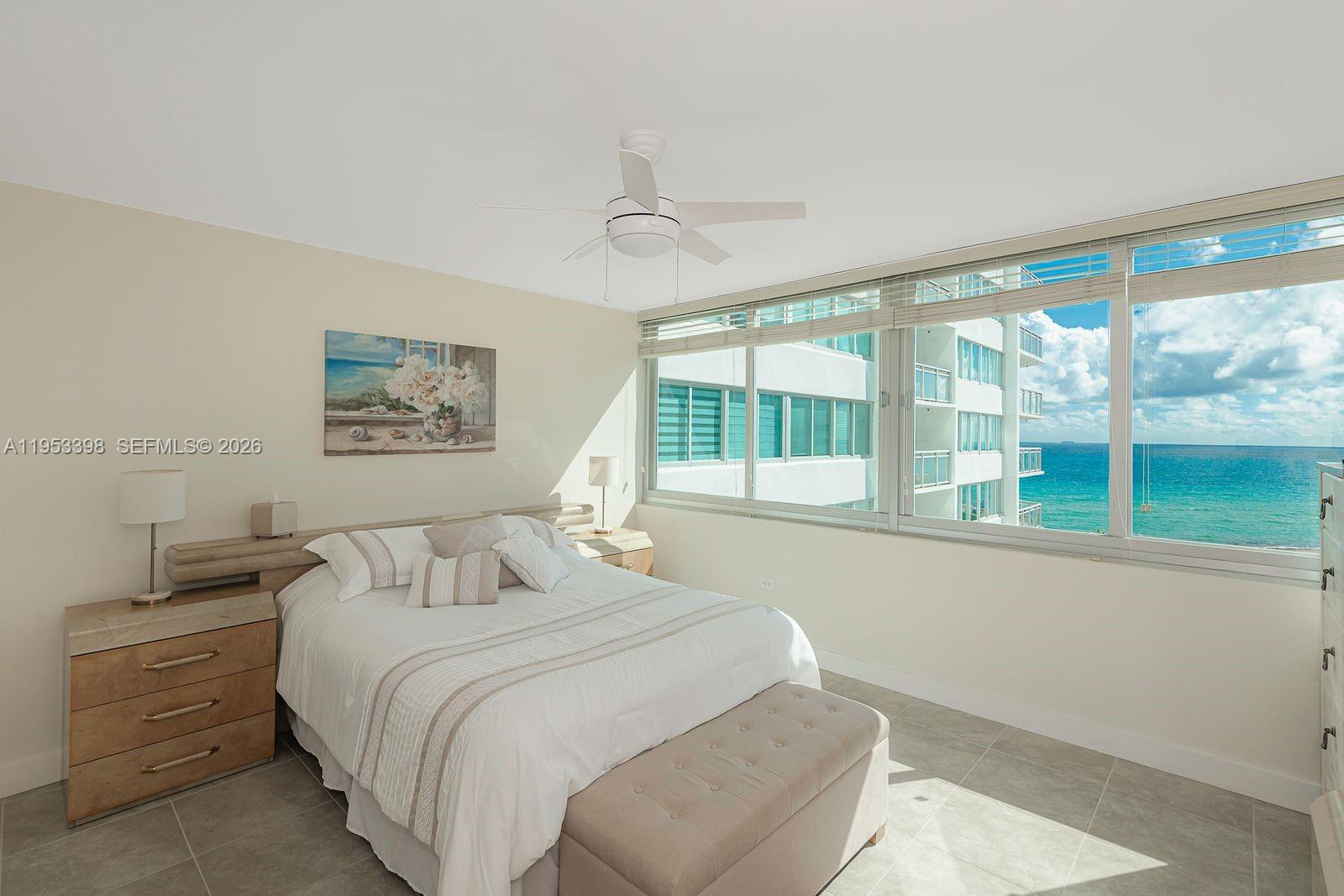 A bedroom features a bed, a ceiling fan, and large windows overlooking the ocean — 7135 Collins Ave # 722, Miami Beach FL 33141, MIAMI BEACH, FL