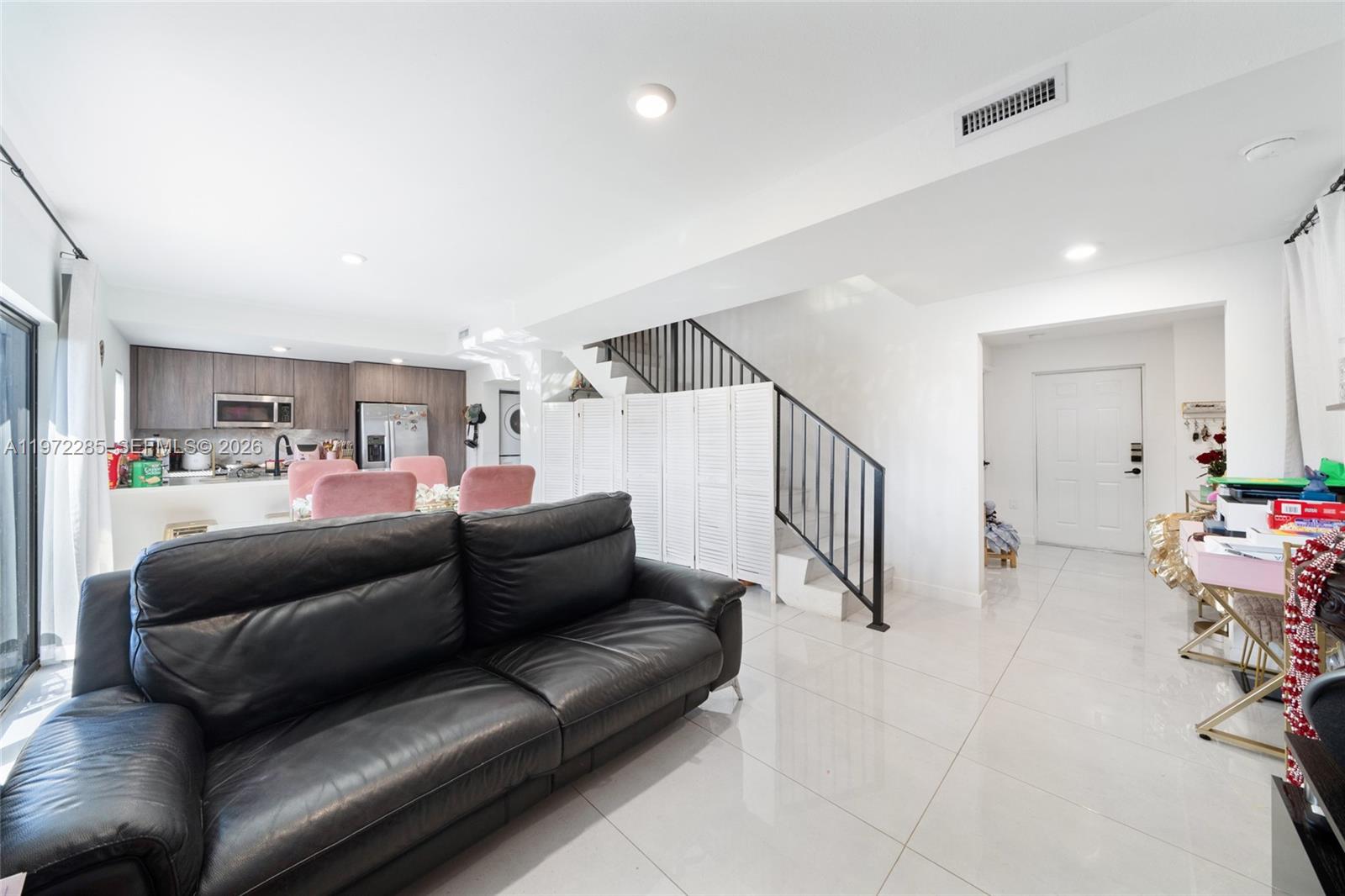 A living room with a black leather sofa, white tile floors, and an open kitchen — 209 NW 13th Pl, Florida City FL 33034, FLORIDA CITY, FL