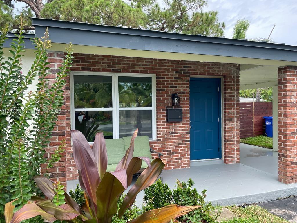 A brick exterior house features a blue front door, a porch, and a green bench — 1029 SW 1st Ave, Pompano Beach FL 33060, POMPANO BEACH, FL