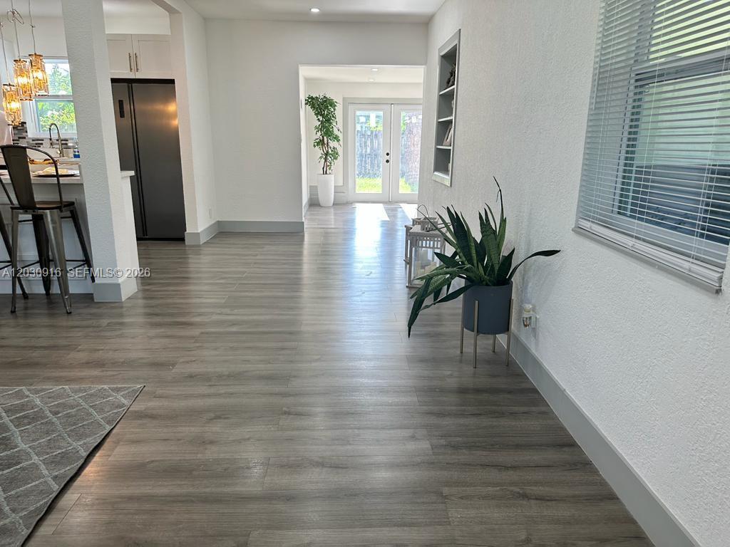 A bright living space features gray wood-look flooring, a kitchen area, and a rear doorway — 1029 SW 1st Ave, Pompano Beach FL 33060, POMPANO BEACH, FL