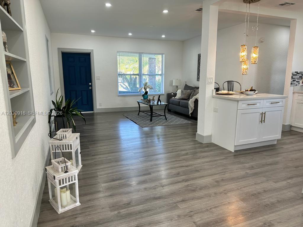 A bright living room features gray wood-look flooring, a blue front door, and white cabinetry — 1029 SW 1st Ave, Pompano Beach FL 33060, POMPANO BEACH, FL