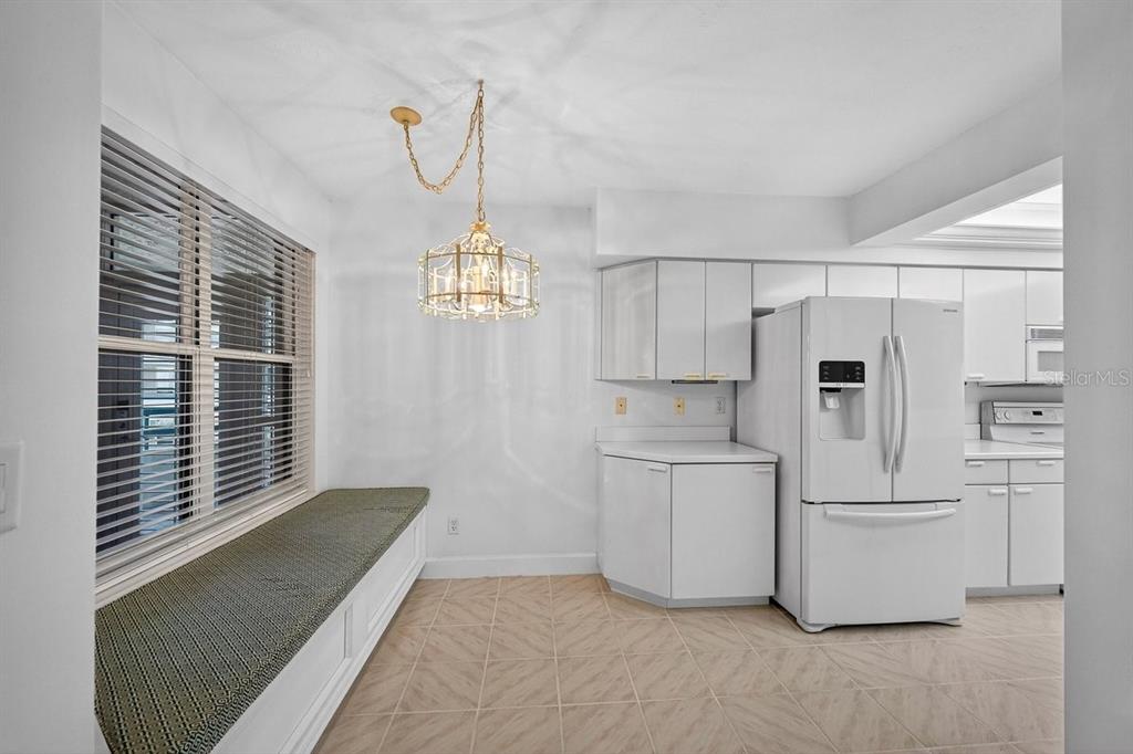 A kitchen breakfast nook features a built-in window bench, tile flooring, and a hanging chandelier — 4555 S ATLANTIC AVENUE UNIT 4411, PORT ORANGE, FL