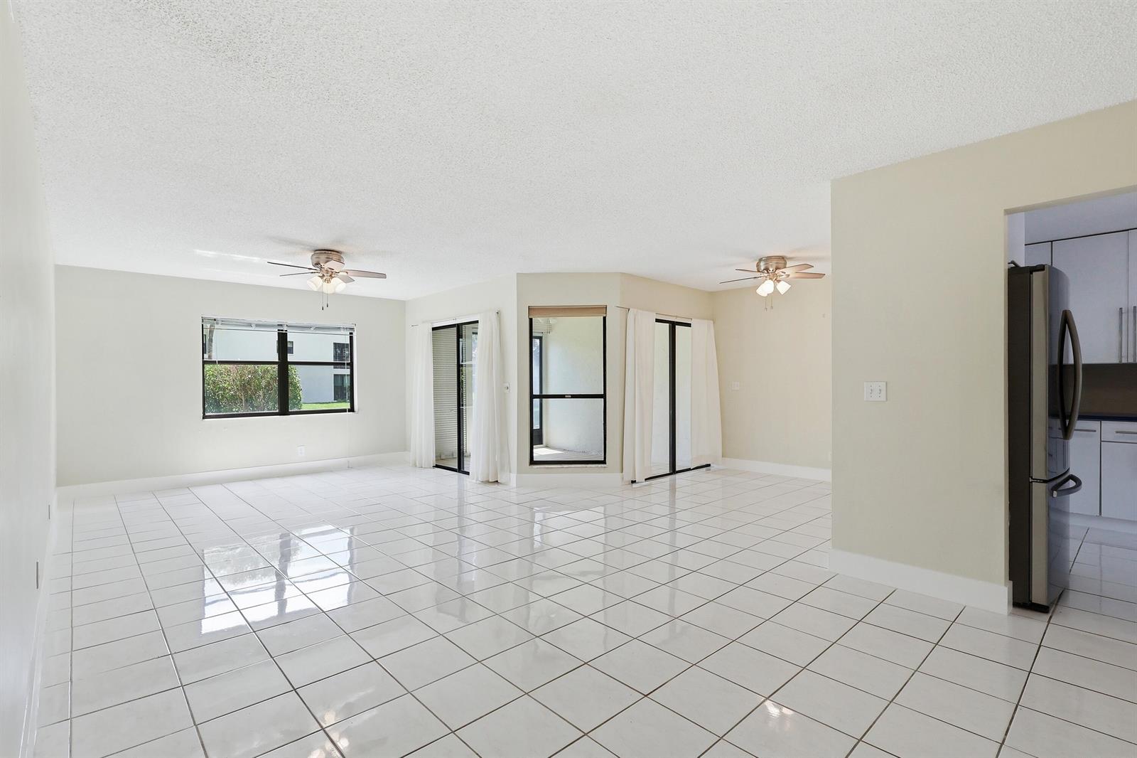 A bright, open-concept living area features white tile flooring, two ceiling fans, and sliding doors — 3242 Perimeter Drive, FL 33467, FL