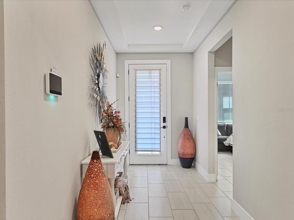 A brightly lit entryway features tile flooring, a white console table, and a front door — 13925 GREEN HAMMOCK PLACE, BRADENTON, FL