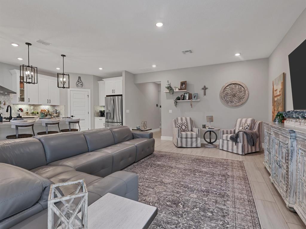 A living room with a grey sectional sofa, two striped armchairs, and an open kitchen — 13925 GREEN HAMMOCK PLACE, BRADENTON, FL