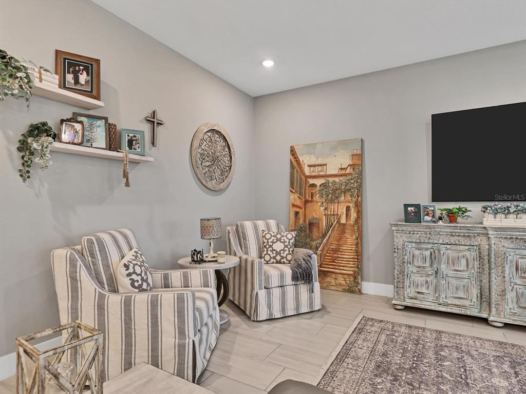 A living room features two striped armchairs, a wooden media console, and wall-mounted shelves — 13925 GREEN HAMMOCK PLACE, BRADENTON, FL