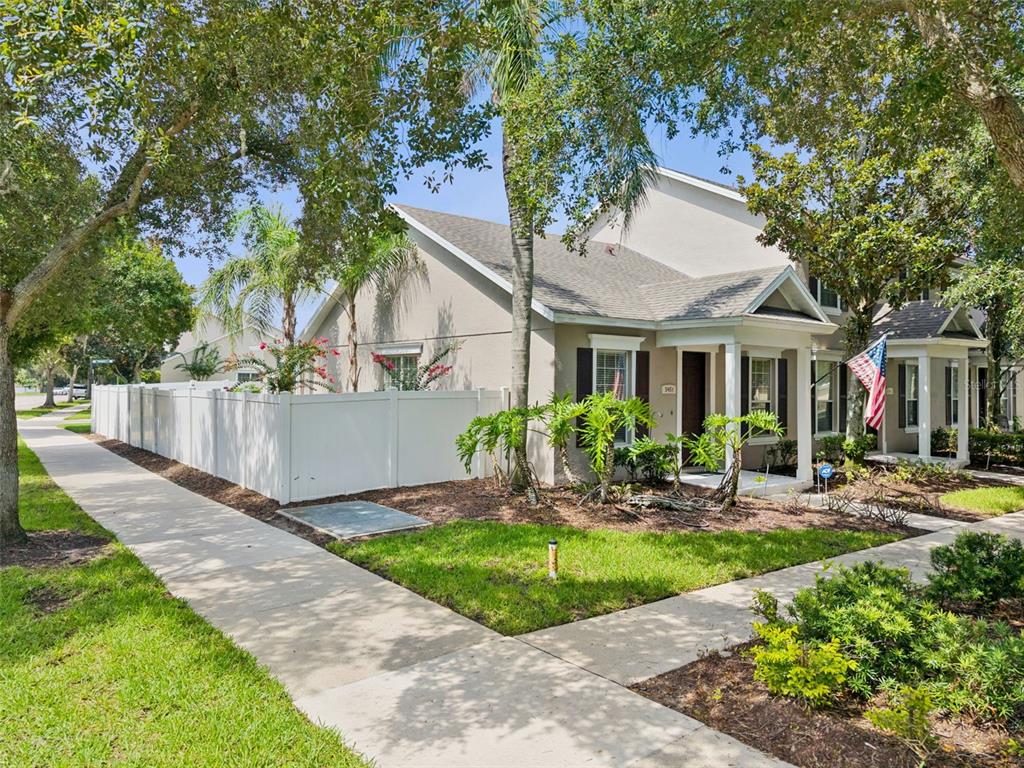 A two-story townhouse with a white vinyl fence, a front porch, and a sidewalk — 5451 KUMQUAT LOOP, WINDERMERE, FL