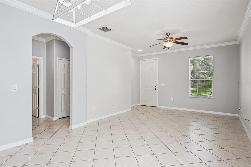 A bright room with light gray walls, tiled floors, a ceiling fan, and an arched doorway — 5451 KUMQUAT LOOP, WINDERMERE, FL