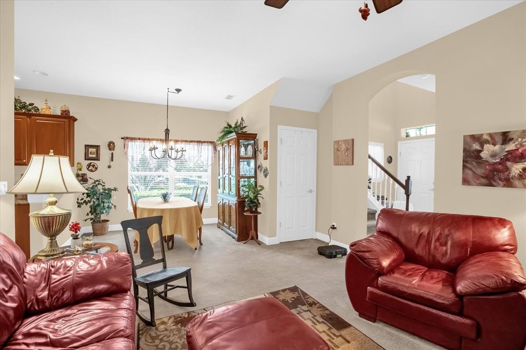 A living room and dining area with carpeted floors, red leather furniture, and a china cabinet — 1338 ALSTON BAY BOULEVARD, APOPKA, FL