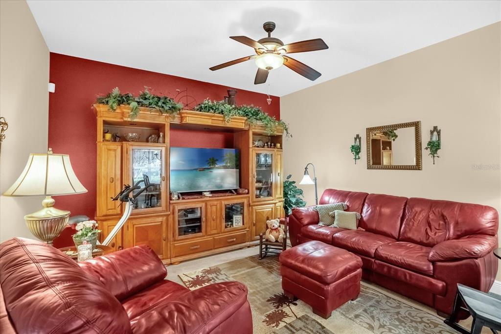 A living room features red leather sofas, a large wooden entertainment center, and a ceiling fan — 1338 ALSTON BAY BOULEVARD, APOPKA, FL
