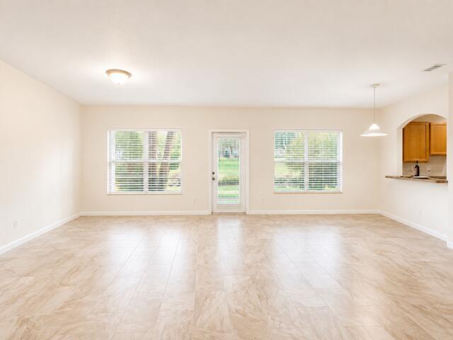 An open living area features light-colored tile flooring, beige walls, and a glass-paneled exterior door — 4406 NE Windmill Palm Way, FL 33463, FL