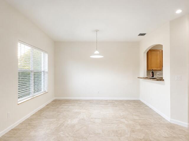A dining area features light-colored tile flooring, a single pendant light, and a kitchen pass-through — 4406 NE Windmill Palm Way, FL 33463, FL