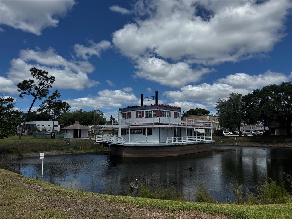 A white paddle-style boat named Village Queen sits in a small pond near buildings — 5917 VILLAGE CIRCLE UNIT 5917, ORLANDO, FL