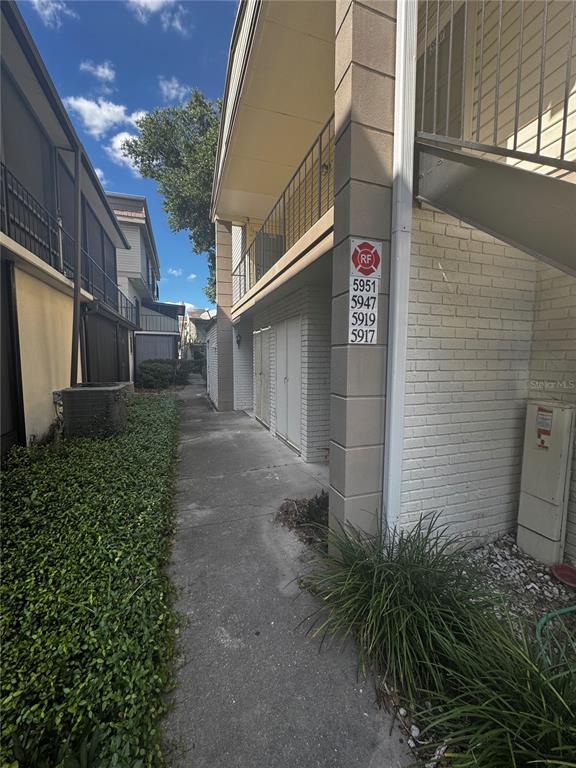A concrete walkway leads between two multi-story apartment buildings with exterior staircases and landscaping — 5917 VILLAGE CIRCLE UNIT 5917, ORLANDO, FL