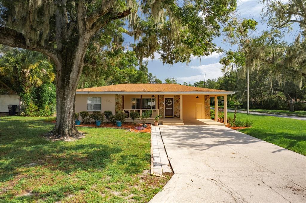 A single-story house with a tan exterior, stone accents, a front porch, and a concrete driveway — 1901 E PARIS STREET, TAMPA, FL