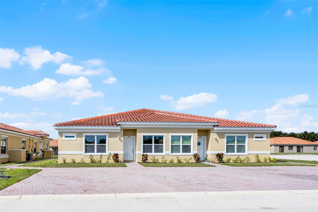 A single-story duplex with a tan stucco exterior and a red tile roof — 1822 CORIANDER DRIVE, KISSIMMEE, FL