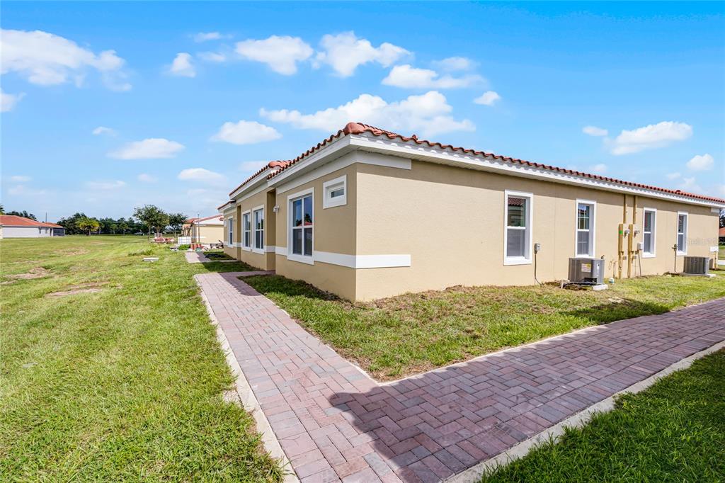 A tan stucco house exterior with a red tile roof and a brick paver walkway — 1822 CORIANDER DRIVE, KISSIMMEE, FL