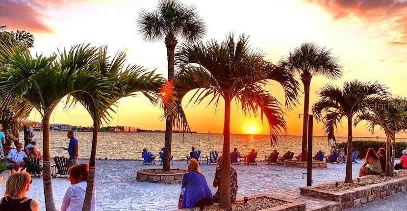 People sit on chairs on a sandy beach watching the sunset by palm trees — 17344 HARRIS AVENUE, PORT CHARLOTTE, FL