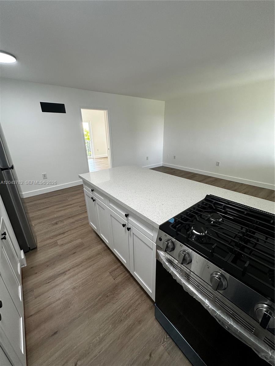 A kitchen island with a white countertop sits in front of a stainless steel stove — 1255 W 49th Pl # E205, Hialeah FL 33012, HIALEAH, FL